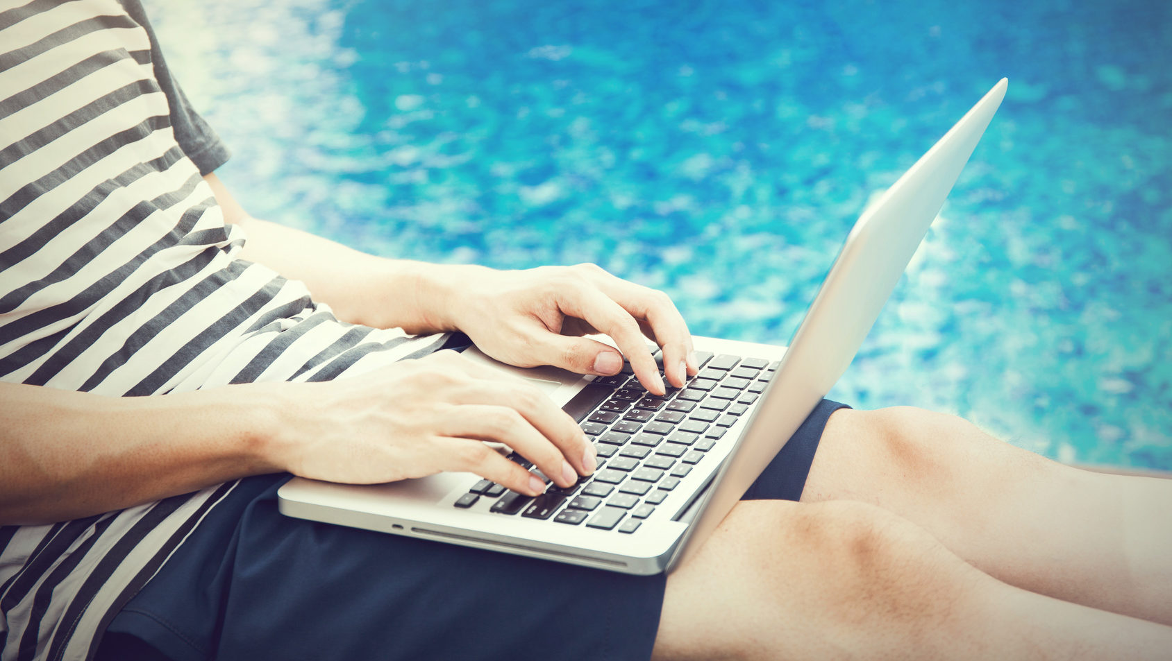 Man using a laptop in the pool on vacation - work anywhere and internet work concept